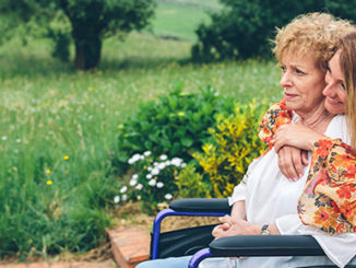 woman sitting in wheelchair, her daughter hugging her